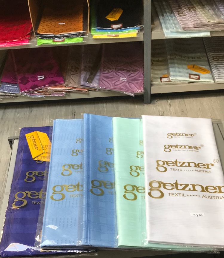 Assortiment de tissus Bazin Getzner authentiques dans leur emballage officiel, montrant les étiquettes de la marque.