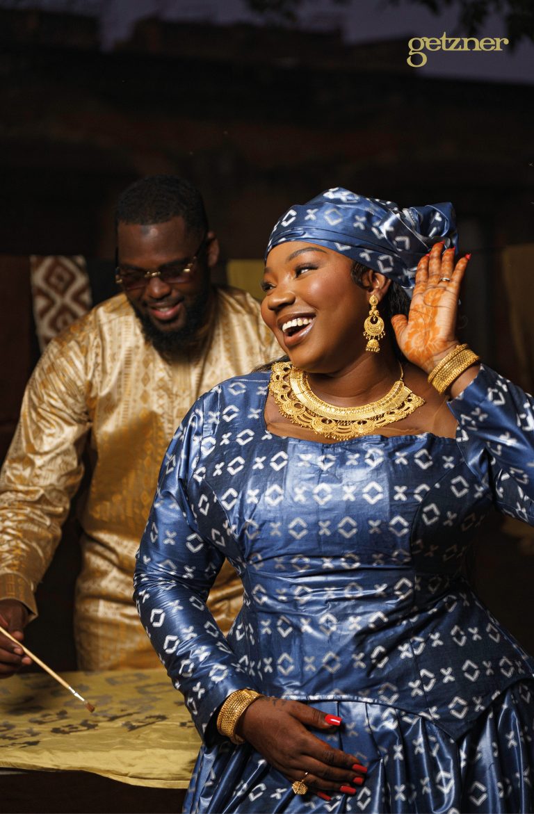 Femme souriante en tenue traditionnelle bazin bleu à motifs géométriques